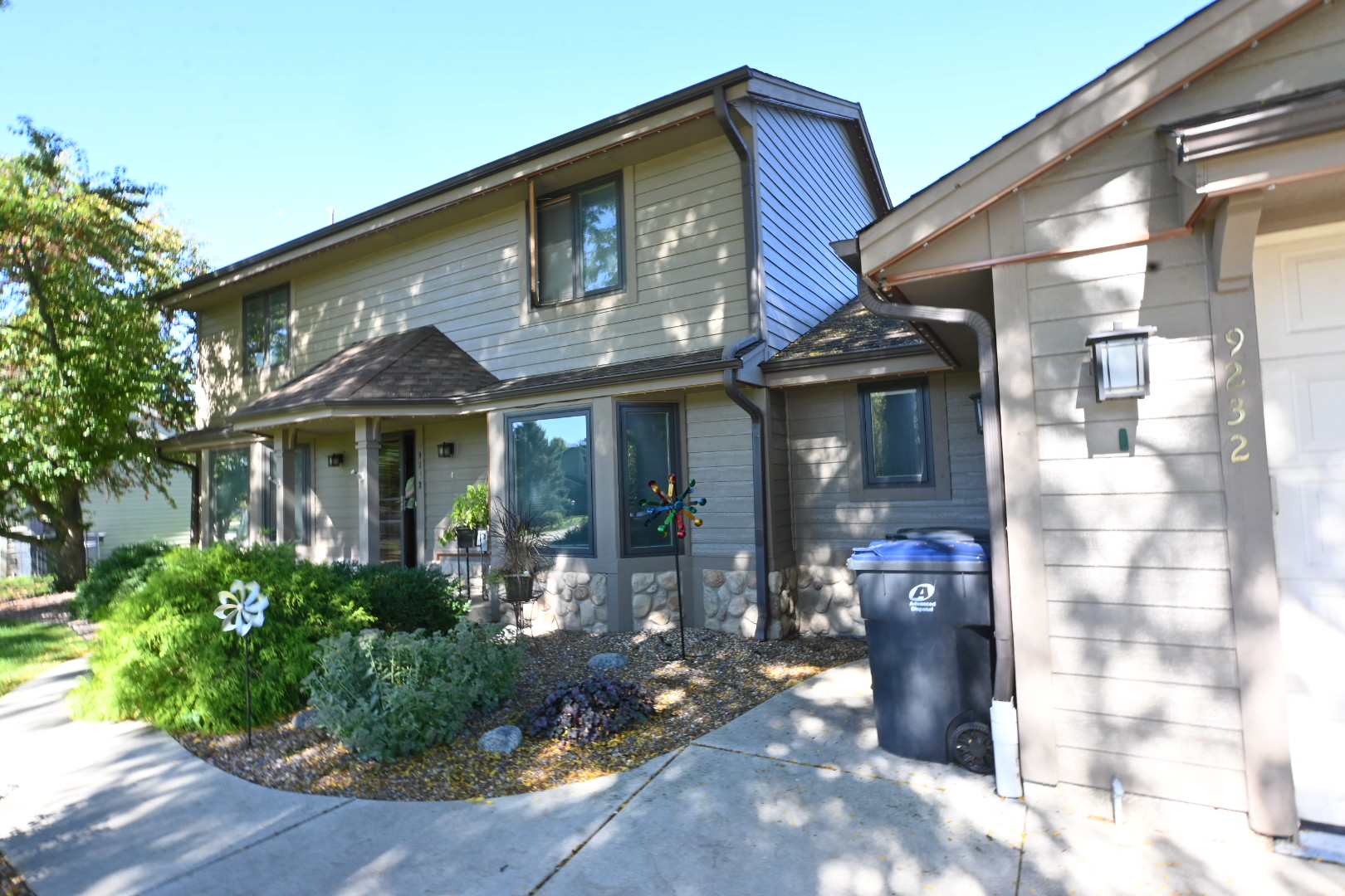 Mequon home with taupe siding, dark trim and mature landscaping