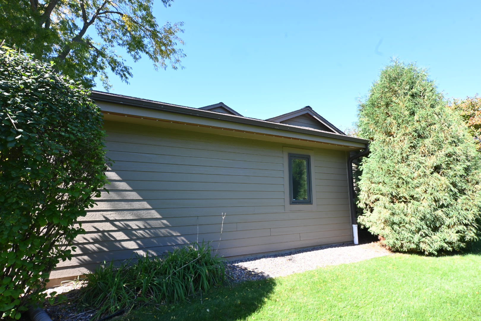 Horizontal siding, window trim and landscaping along the side elevation.