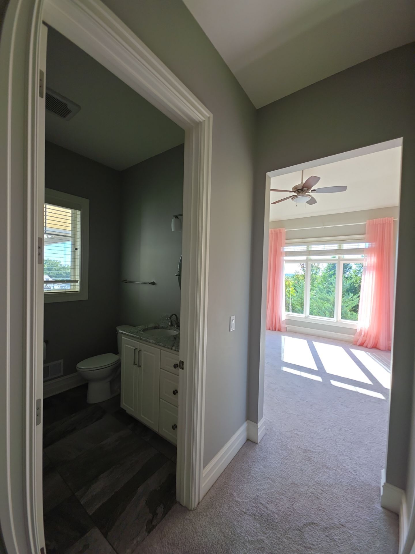 Neutral hallway walls and crisp white door trim opening into a sunlit bedroom