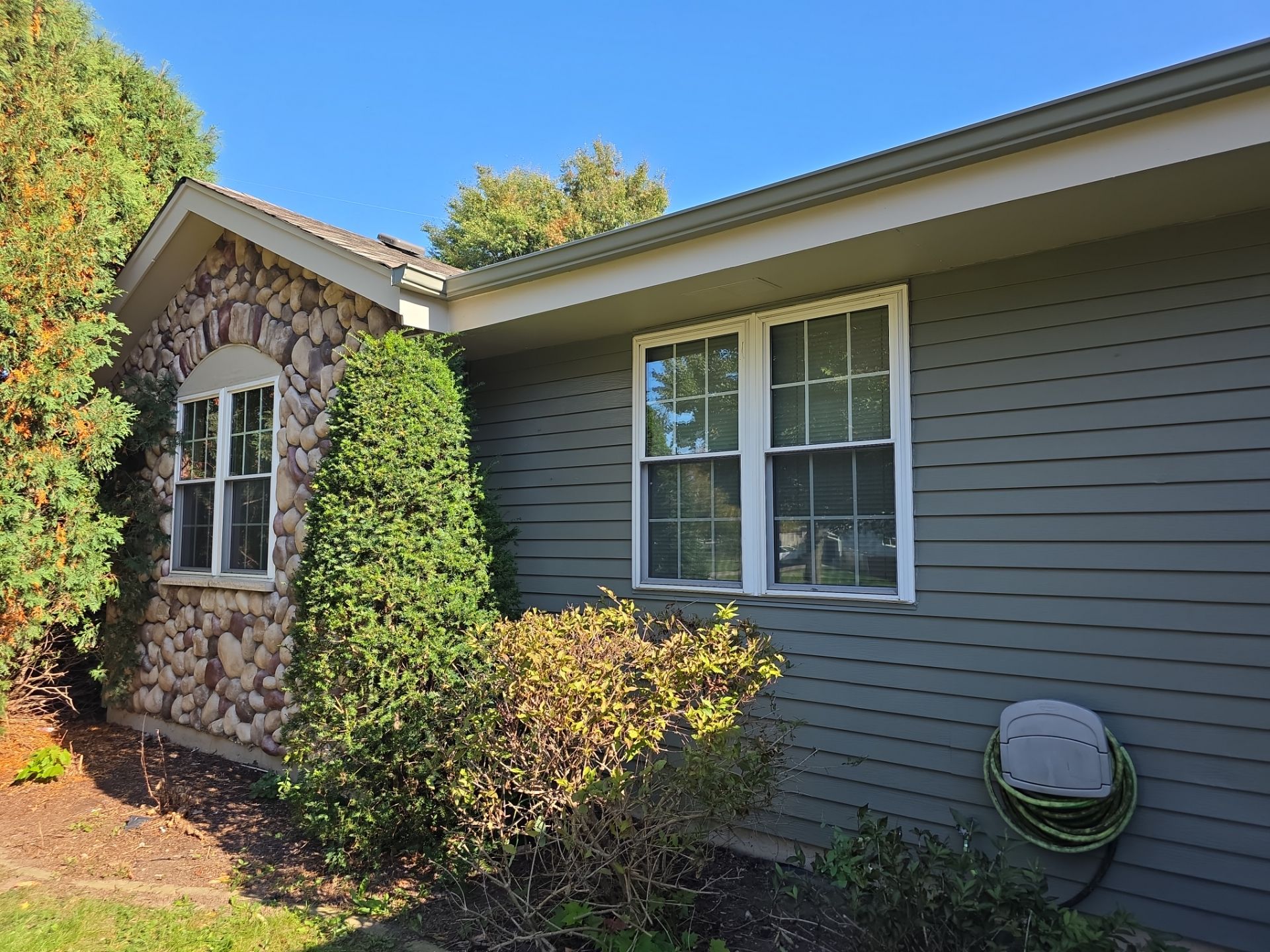 Oak Creek home front with gray-green siding, white windows and stone accents