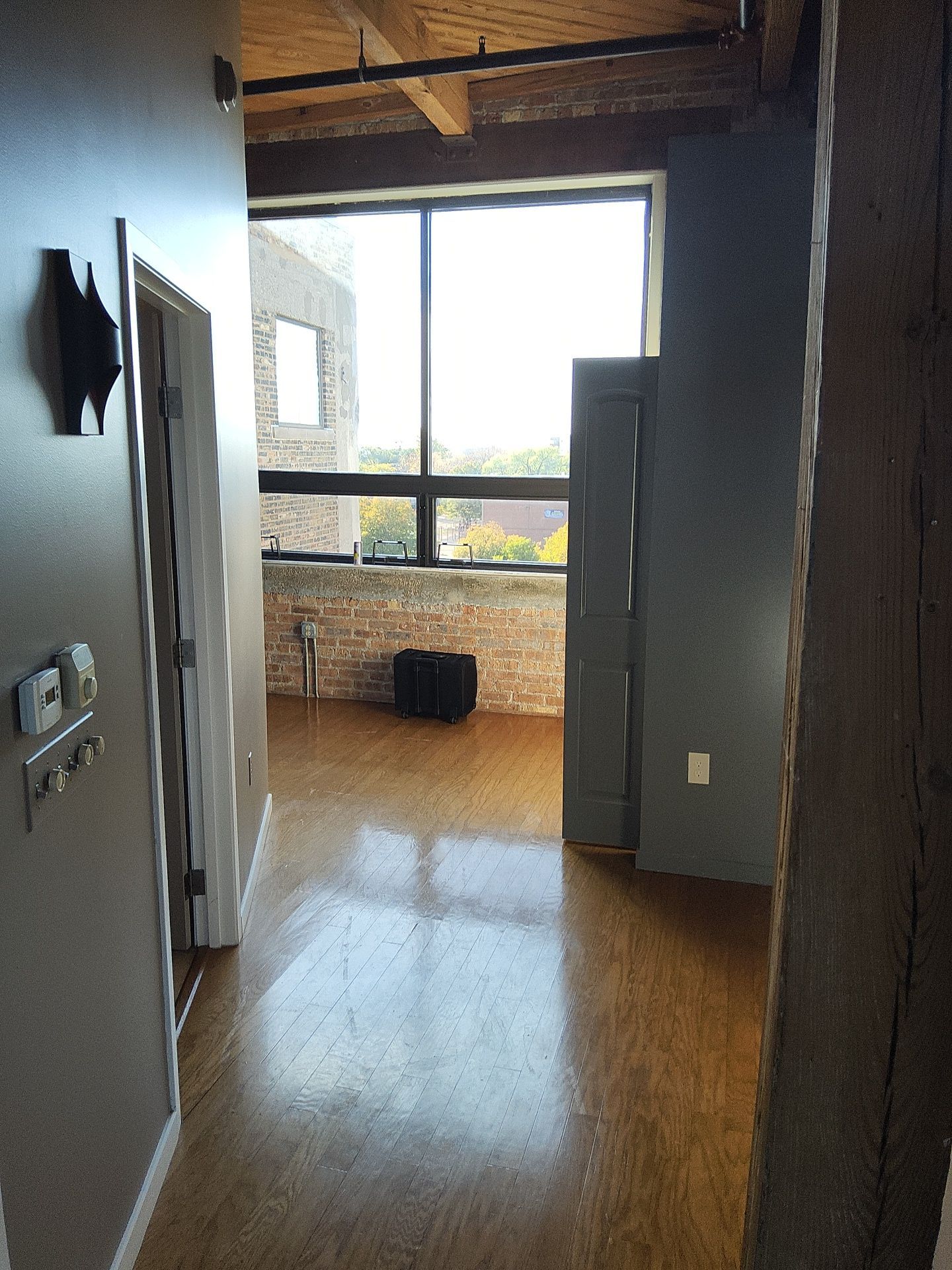 Blue-gray loft walls and gray doors beside exposed brick and tall windows