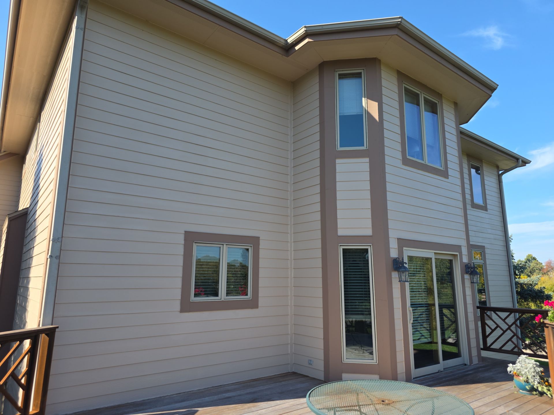 Hartland deck surface beside finished siding, bay windows and a patio table