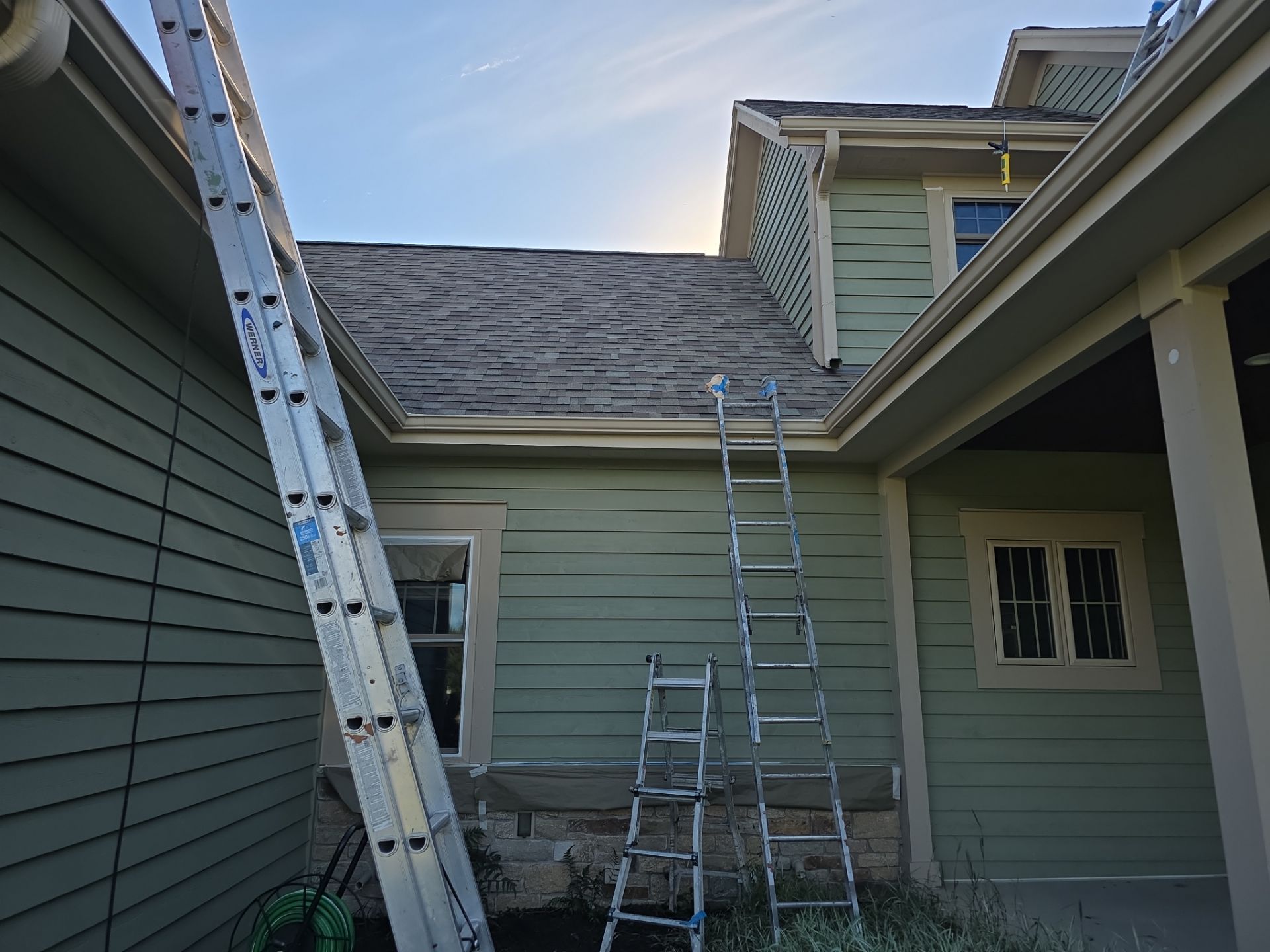 Side courtyard with green siding and window masking during exterior painting