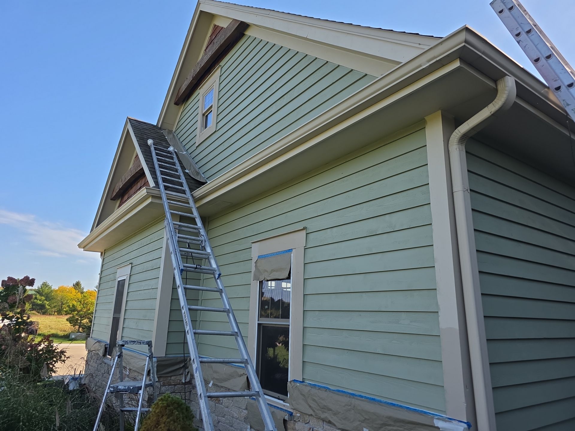 Green siding and cream trim with ladders and masked windows in Dousman