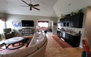 New Berlin living room with neutral walls, white vaulted ceiling, dark built-ins and wood flooring