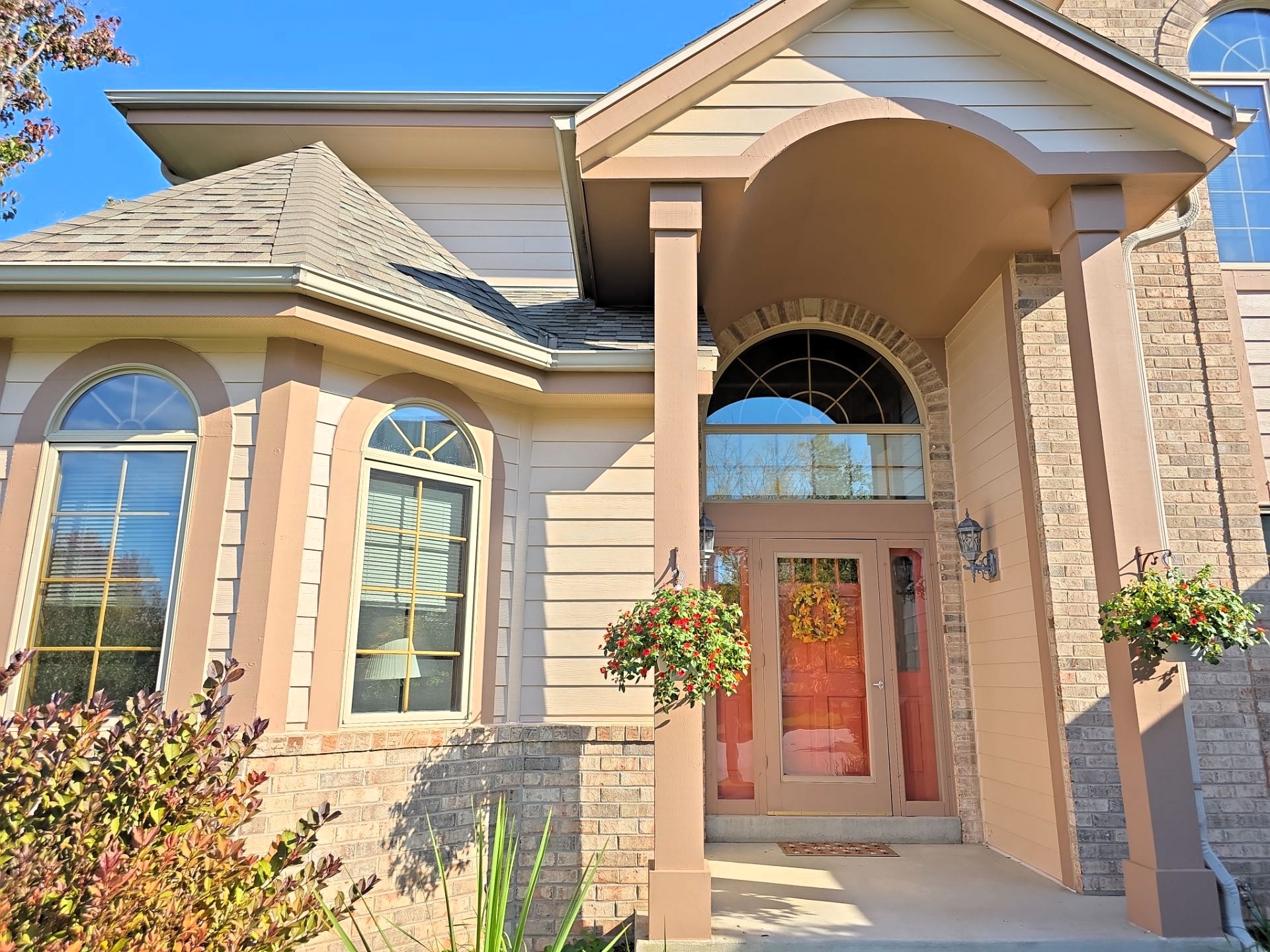 Hartland front entry with arched windows, contrasting trim and hanging flower baskets