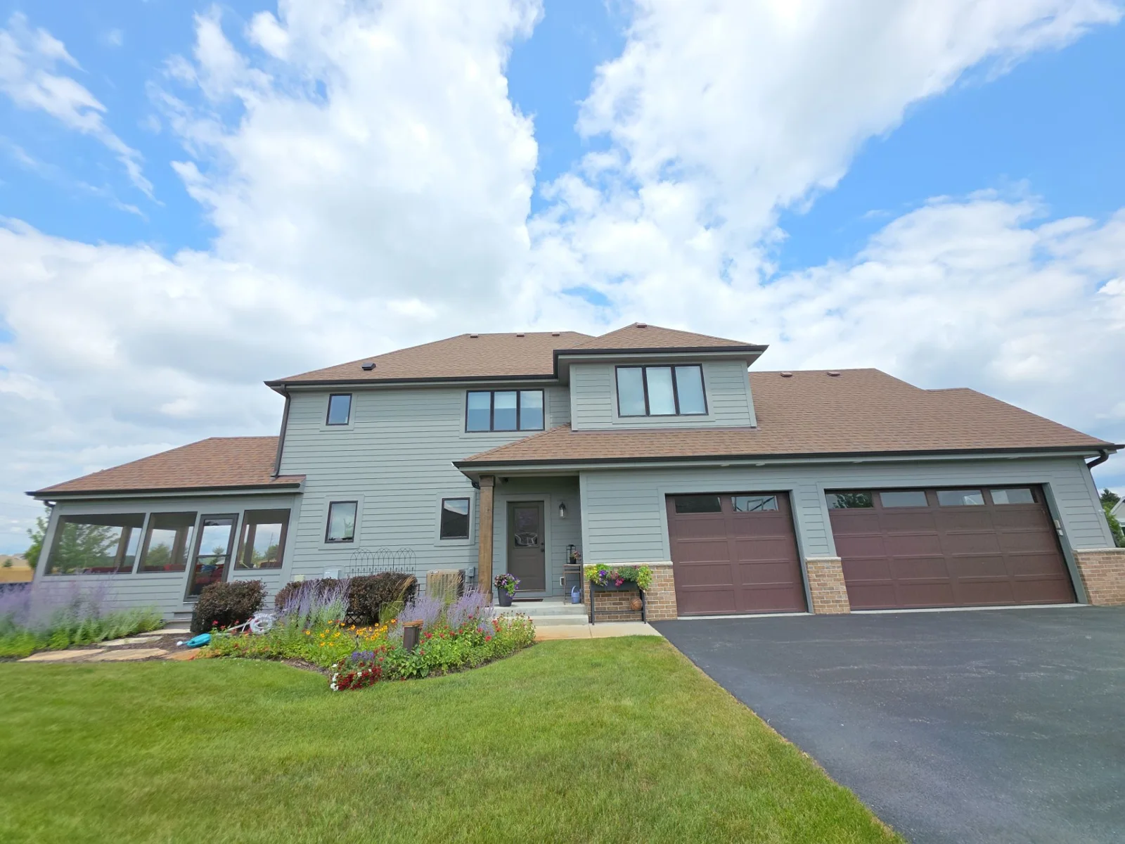 Oconomowoc home with finished gray siding, dark trim and a brown garage door