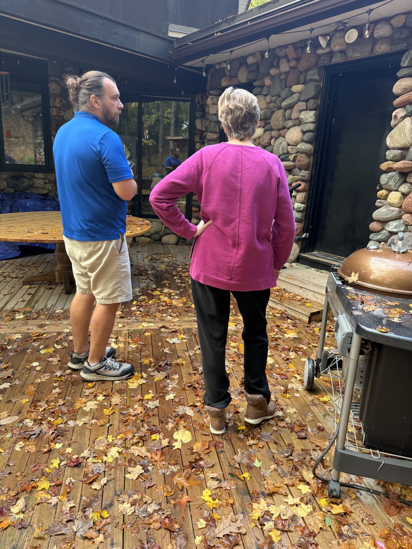 Matt and a homeowner reviewing exterior details beside stone walls and a wood deck in Hubertus