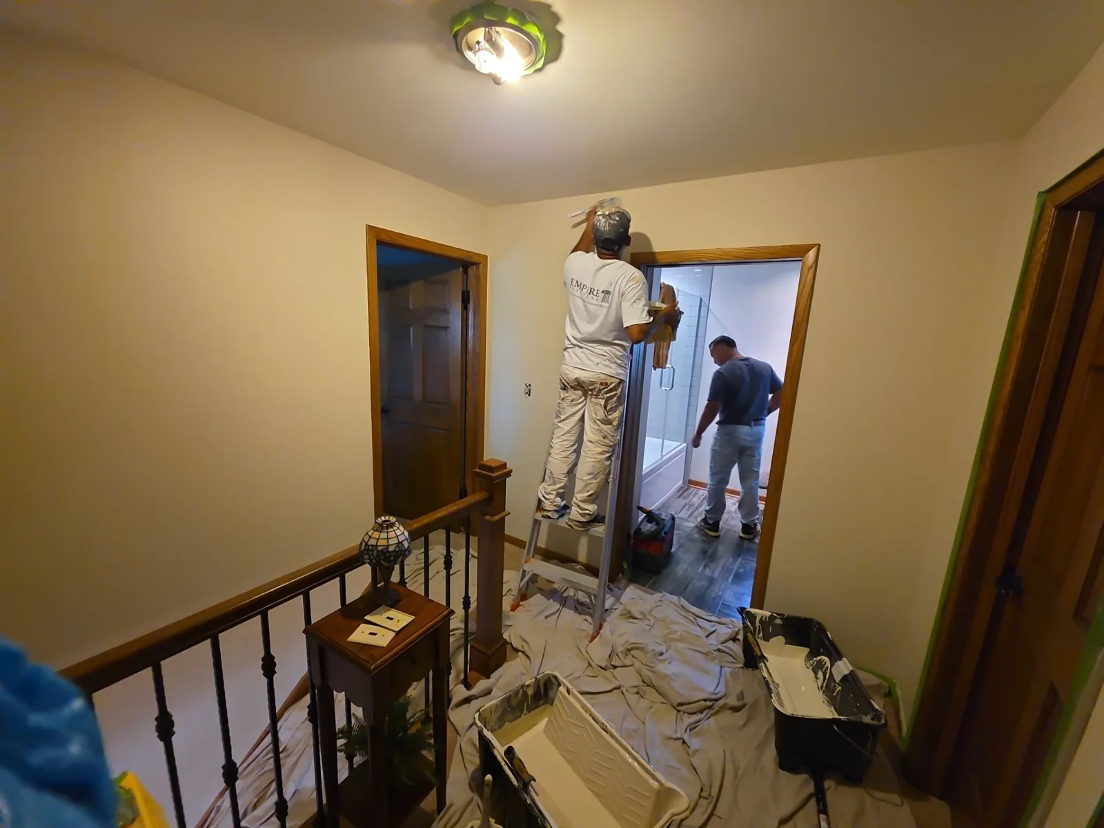 Crew at work: interior painting around an upstairs doorway, with the work area protected.