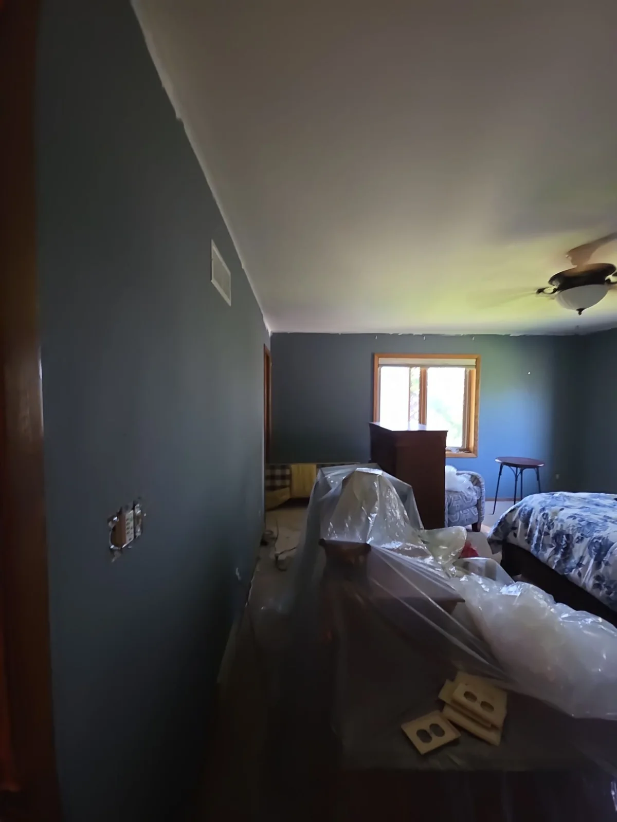 During interior preparation: furniture is covered and supplies are staged in the room.