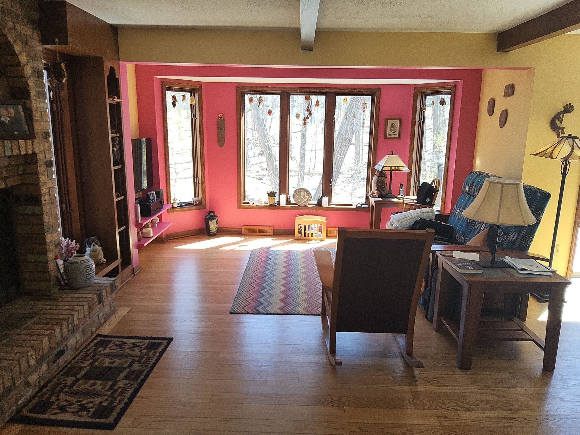 Living room with warm yellow walls, a red window wall and a stone fireplace